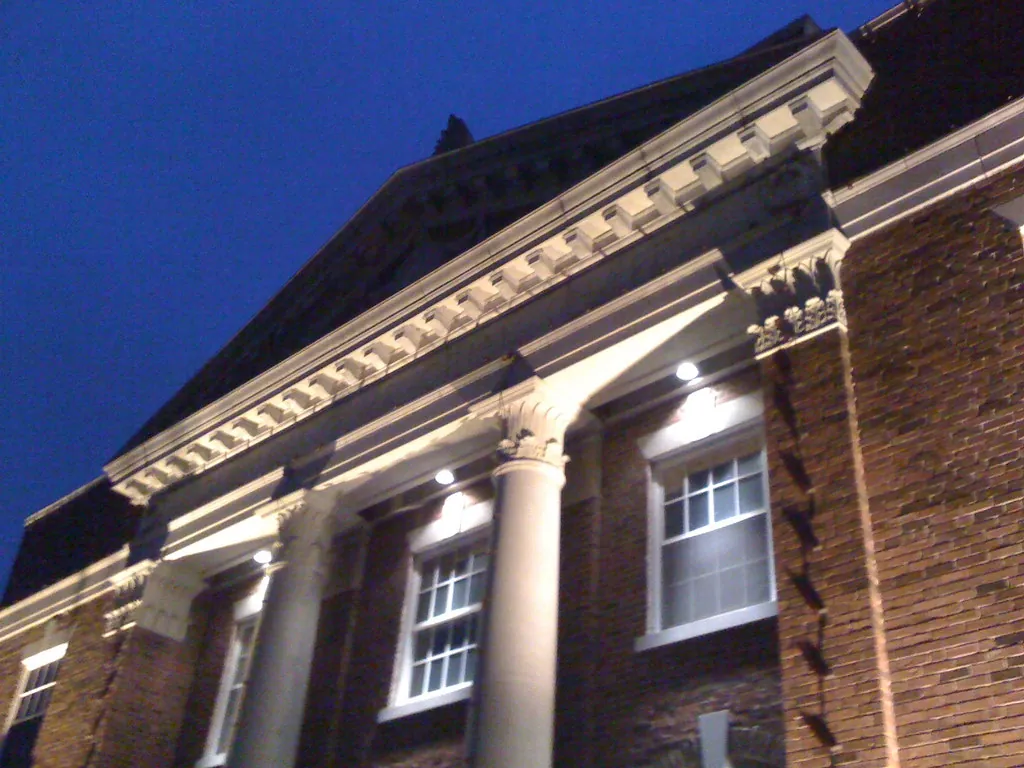 Brick building with lit columns and gable at dusk